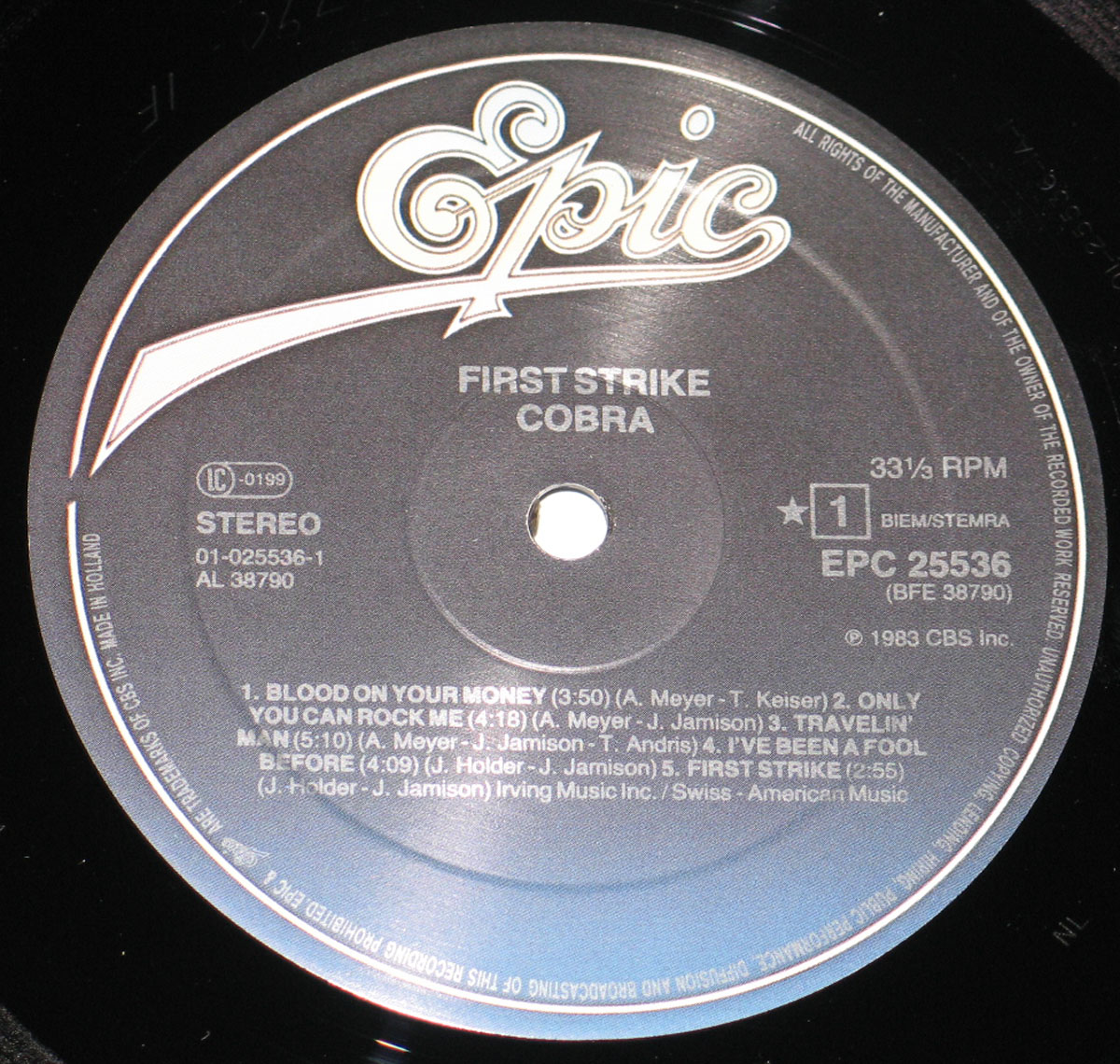 Close-up of Side One label of Cobra's First Strike vinyl record, showing the Epic logo, track list, and catalog details including EPC 25536 and AL 38790, pressed in Holland.